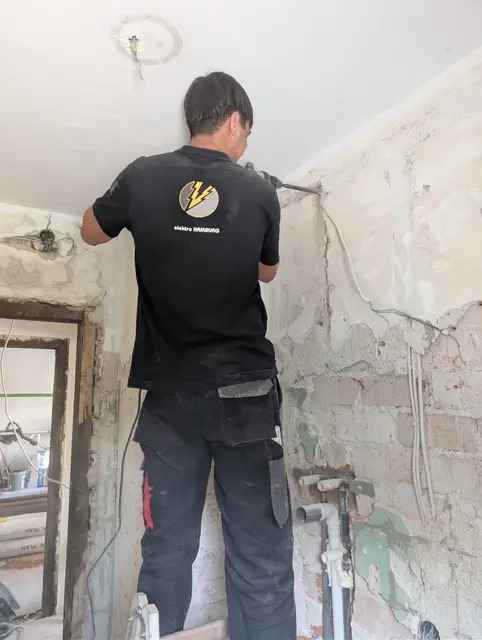 Monteur arbeitet an einer bis auf den Ziegel freigelegten Altbauwand