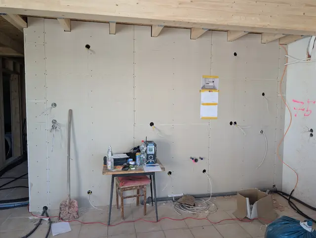 Fertig beplankte Wand mit vorbereiteten Auslässen, davor ein Messgerät auf dem Tisch