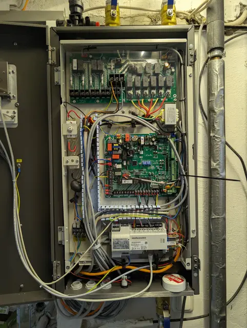 Geöffneter Steuerschrank mit Steuerplatine, Reihenklemmen und abgehenden Leitungen