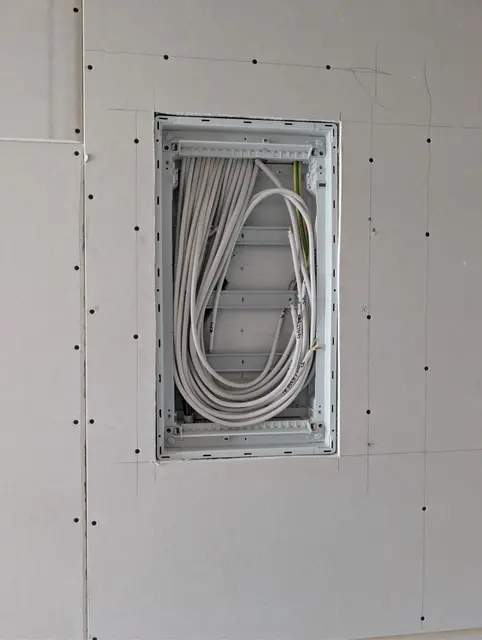 Verteilergehäuse in einer Trockenbauwand, die Zuleitungen liegen aufgerollt bereit